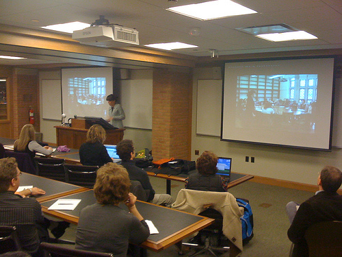 Teaching with Skype Teacher standing in front of classroom with projector screens
